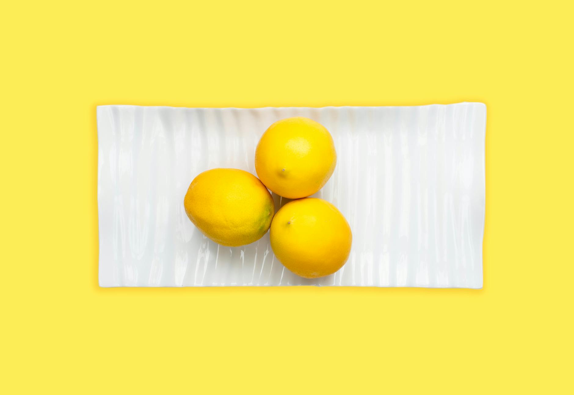 Ein blauer Vibrator umgeben von Blumen und Orangenscheiben auf gelbem Hintergrund, der Neubeginn und Erneuerung symbolisiert