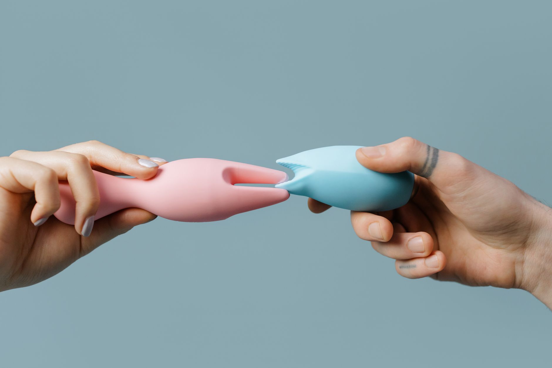 Pastellfarbene Sextoys in Händen, Symbol für achtsame Selbstfürsorge nach der Geburt